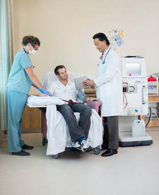 Male patient speaking to a doctor and nurse during his dialysis treament.