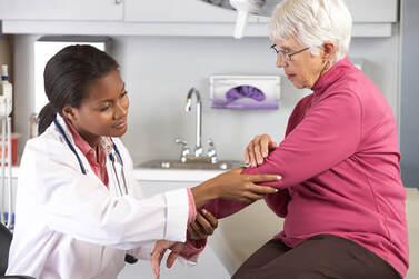 Doctor helping an older patient with elbow pain.