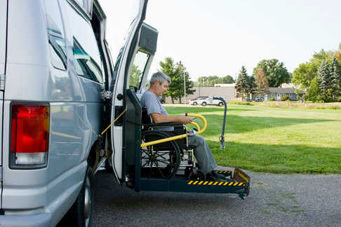 A patient in a wheelchair leaving the van ramp.
