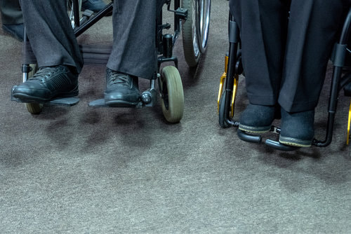 Two men's legs on a separate wheelchairs.