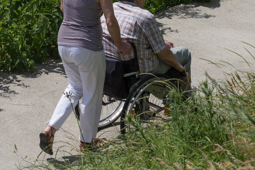 Female pushing a male on a wheelchair.